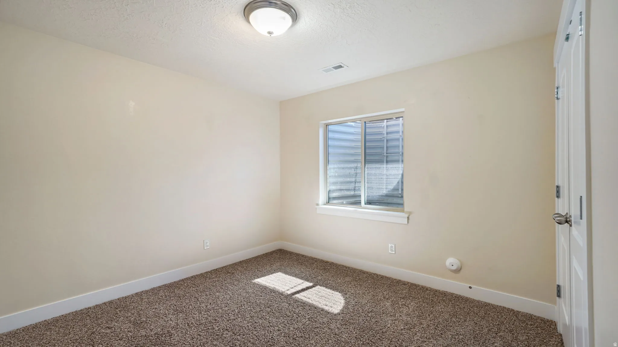 Carpeted room featuring a white paneled door, light-colored walls, and a window with blinds
