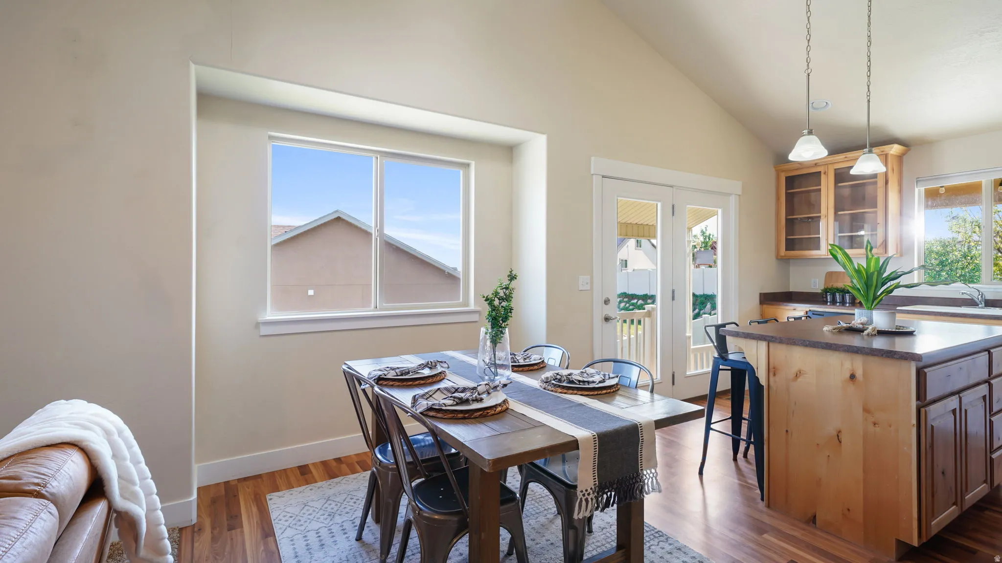 Open-concept living area featuring vaulted ceilings, wood-finish flooring, and a kitchen island with countertop seating