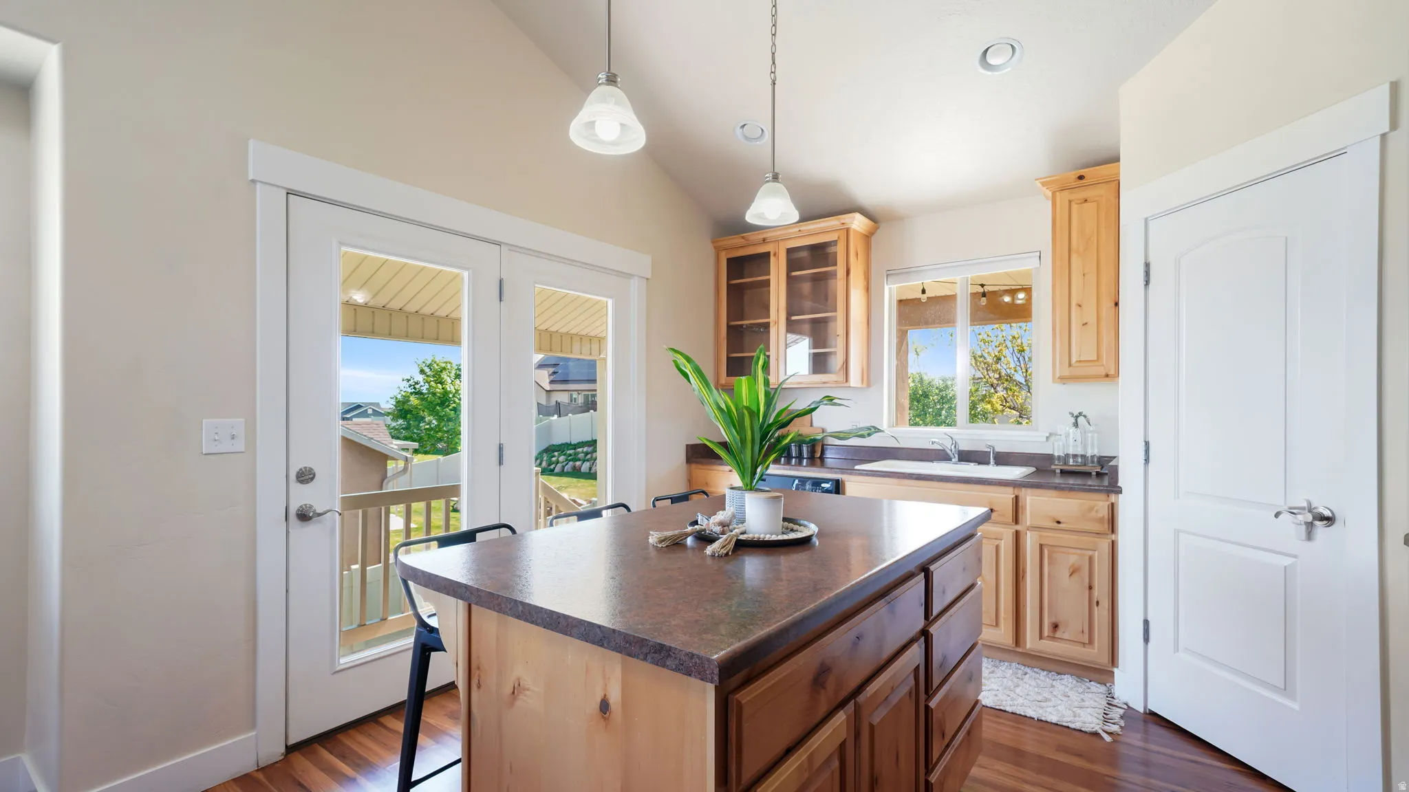Kitchen with a wood-finish island and dark countertop, light wood cabinetry, and a white sink