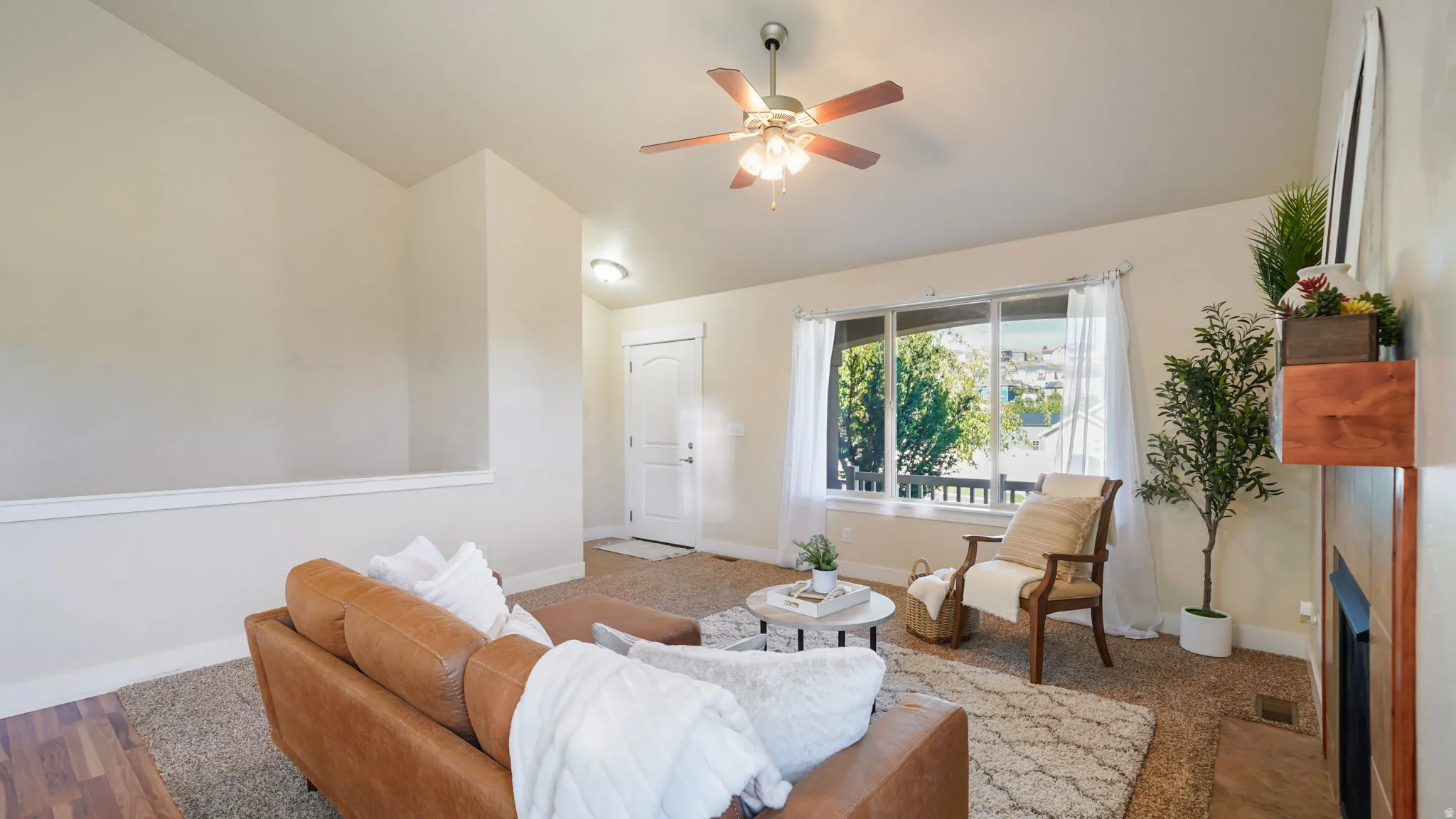 Spacious living area featuring neutral-toned walls, a carpeted floor, and a prominent window