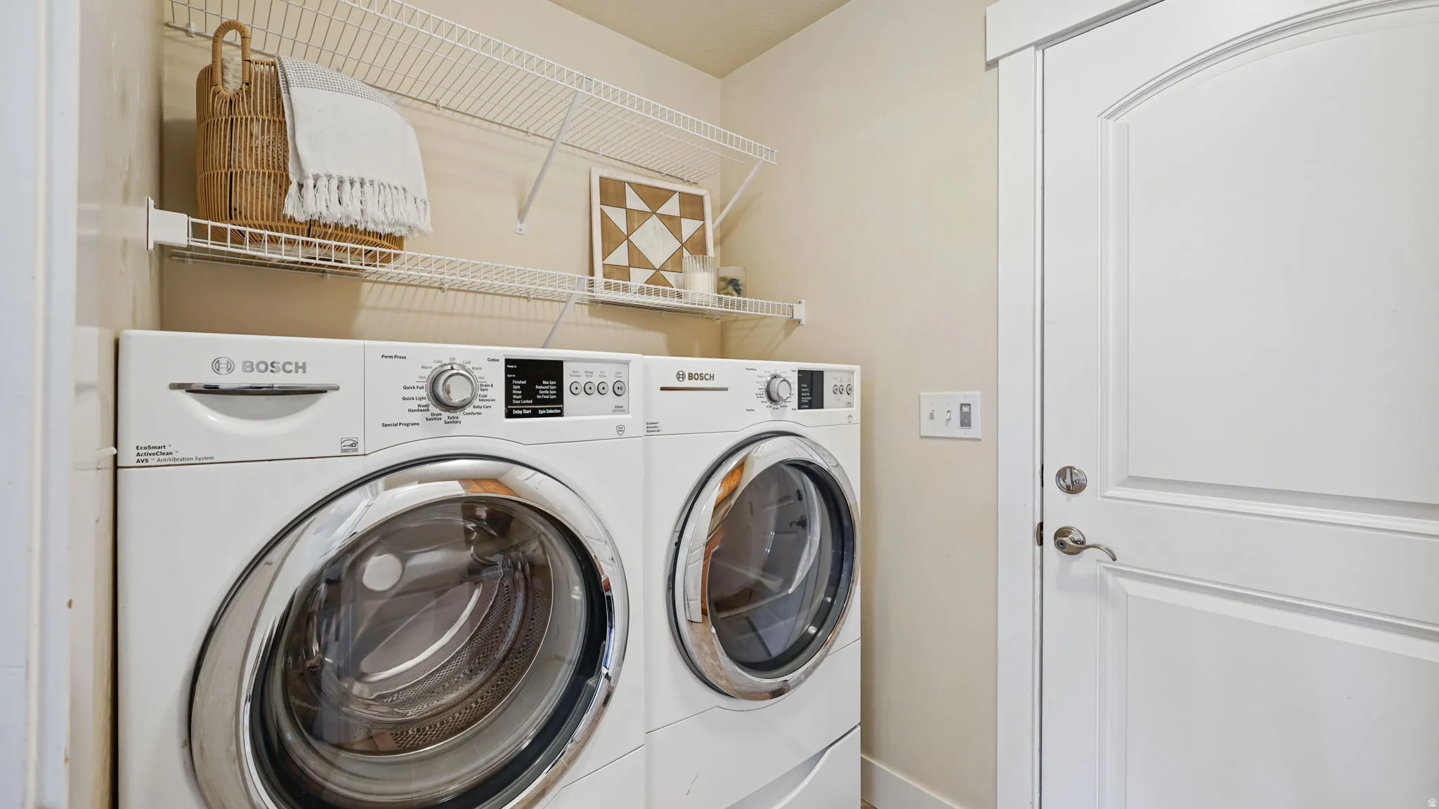 Laundry area featuring a stacked washer and dryer, wire shelving, and a white paneled door
