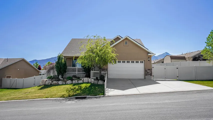 Single-family residence featuring a two-car garage, front porch with white railings, and a tiered rock landscaping design