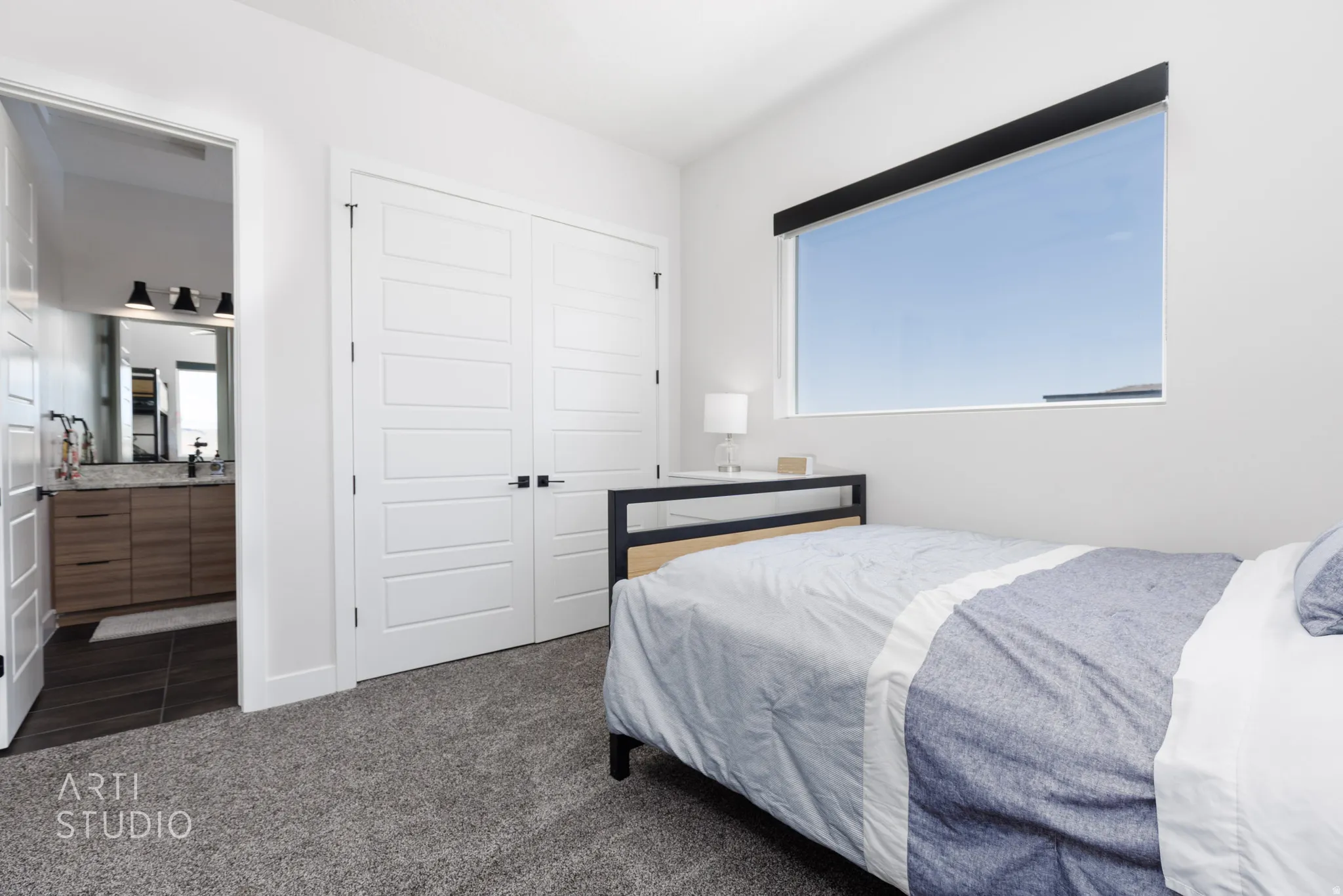 Spacious room featuring plush carpet flooring, a wide horizontal window, and a built-in closet with double white panel doors and black hardware