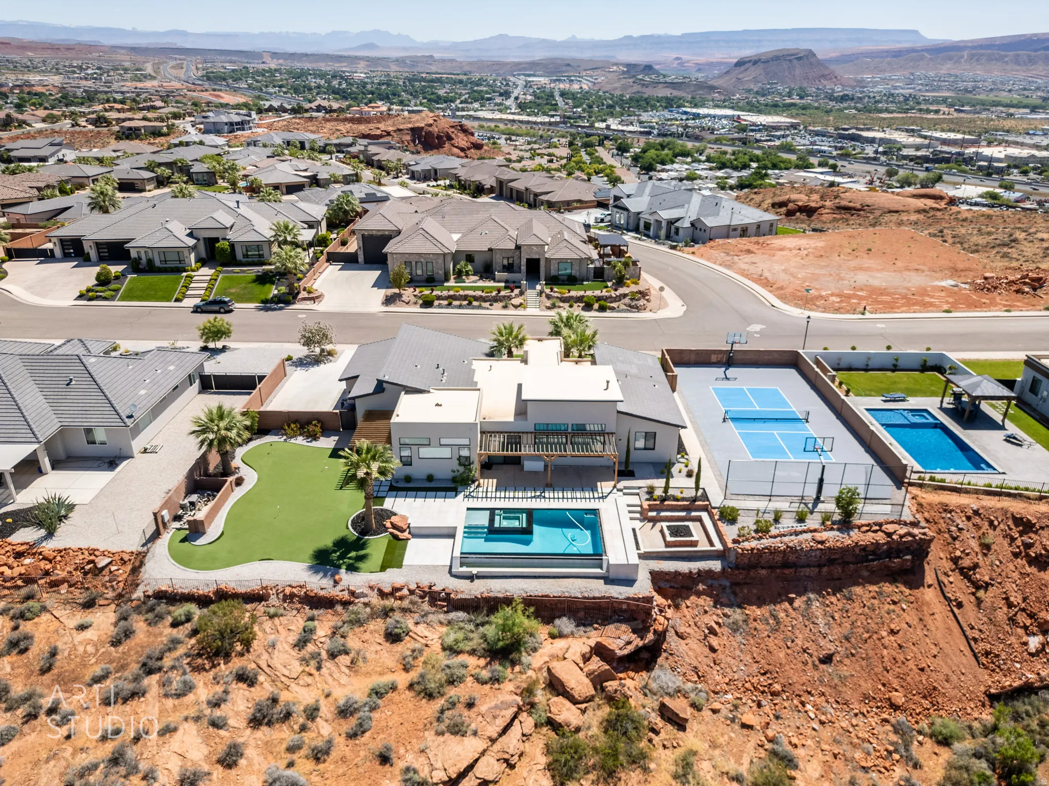 Modern desert home featuring a private tennis court, two swimming pools, a built-in fire pit, and a putting green