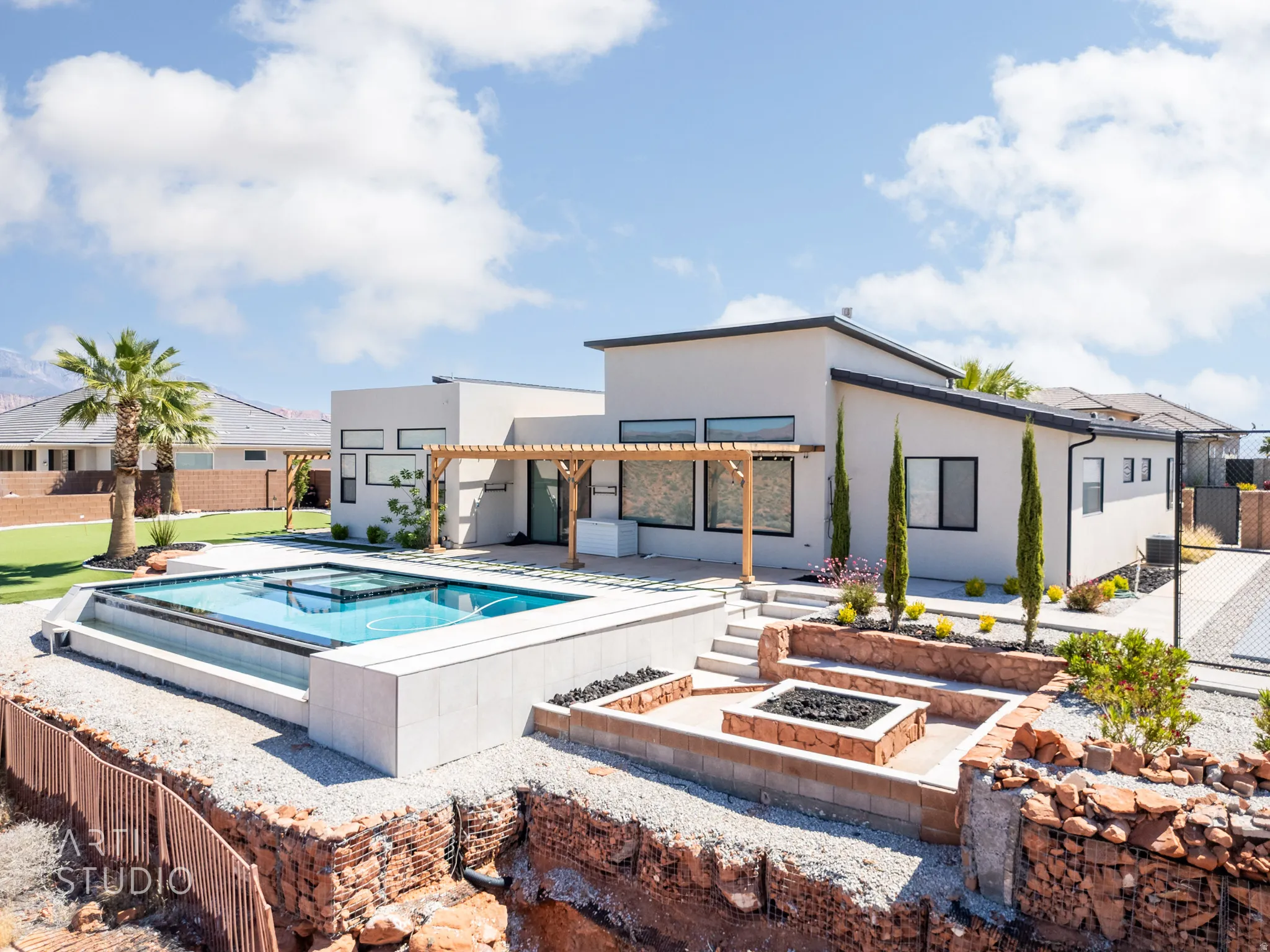 Modern exterior featuring a swimming pool with integrated spa, an outdoor fire pit area, multiple pergolas, and tiered landscaping