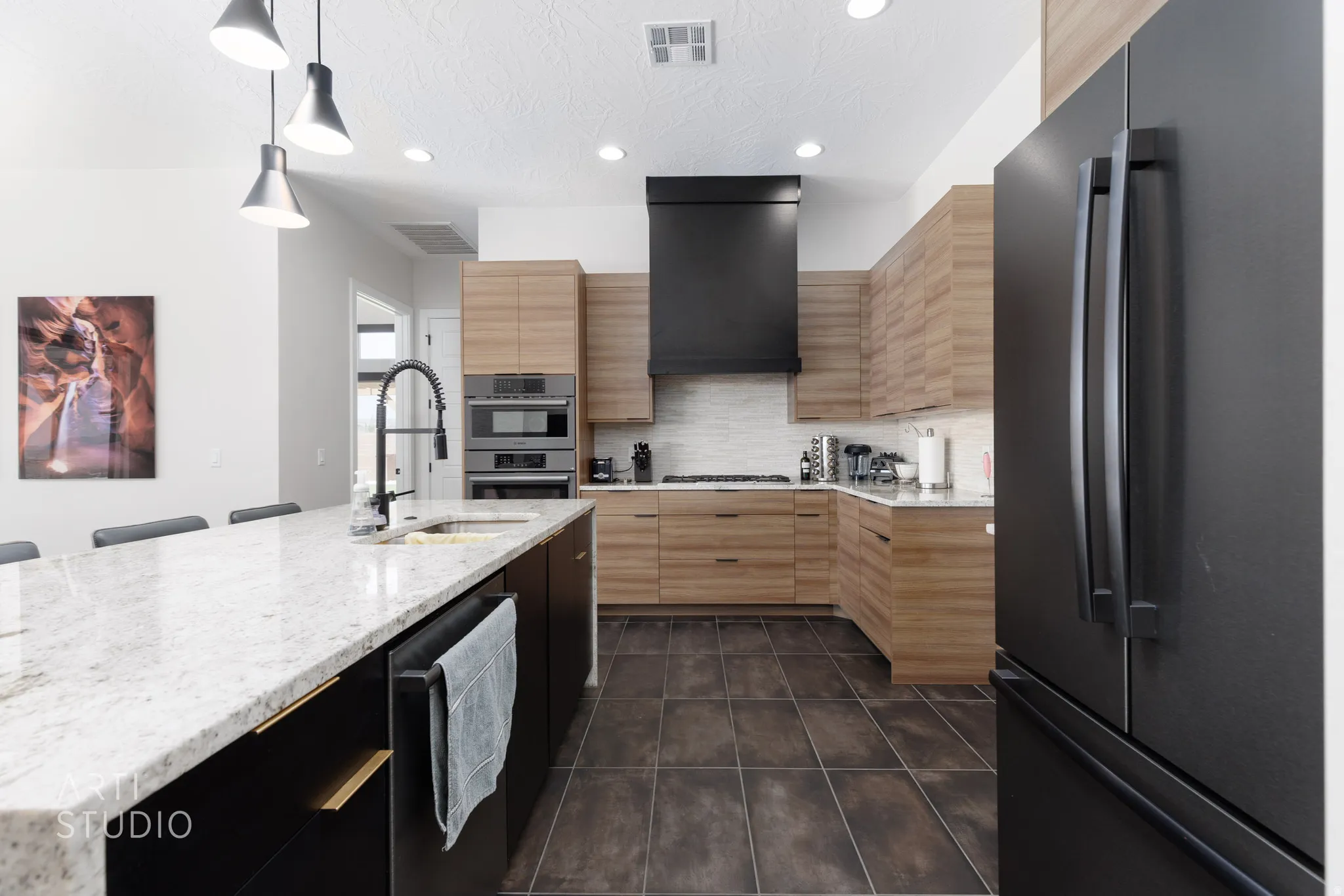 Modern kitchen featuring a large island with a light-toned countertop, a matte black gooseneck faucet, and a built-in sink