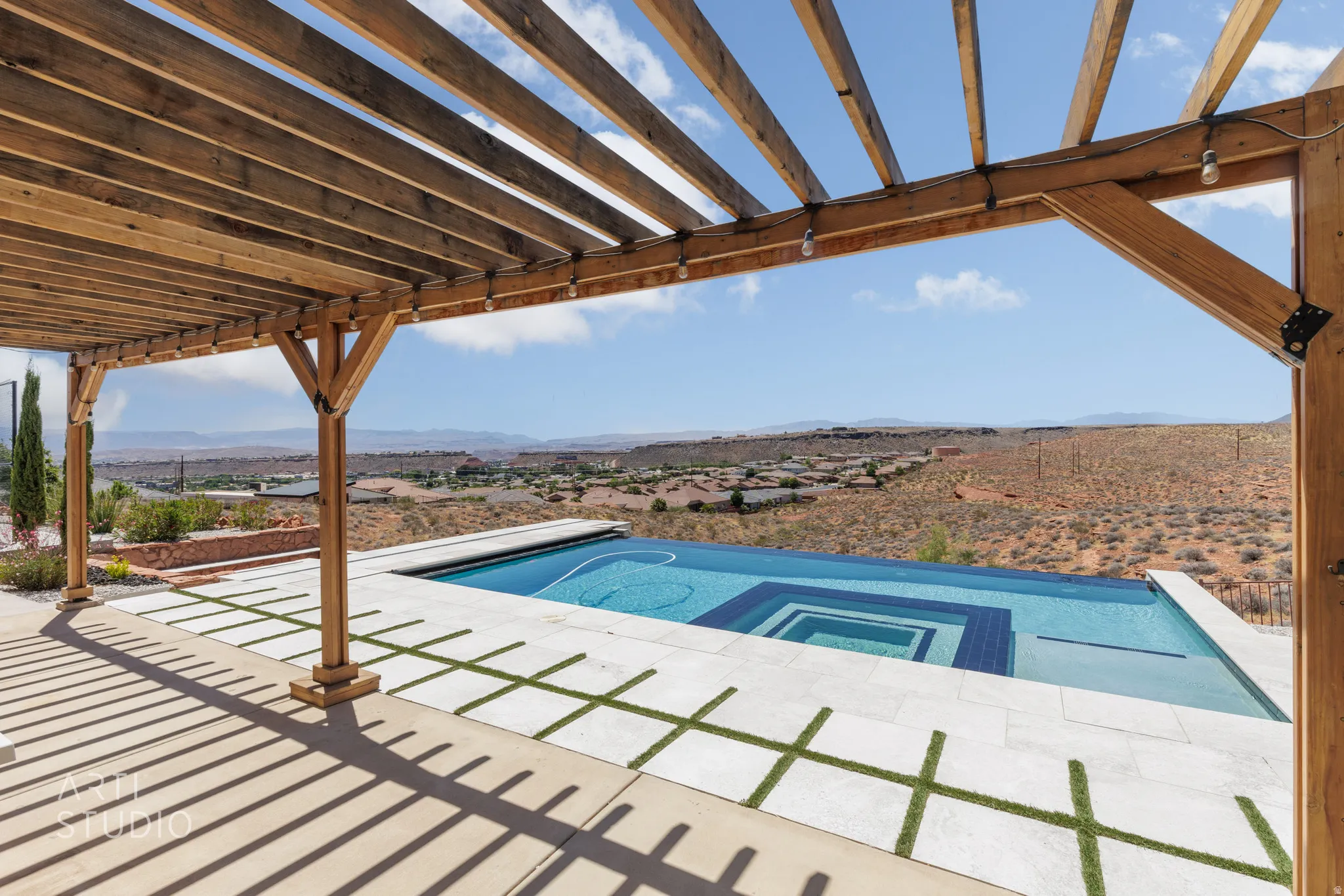 Outdoor living area featuring a wooden pergola, an infinity-edge pool with integrated spa, and a tiled patio with artificial turf accents