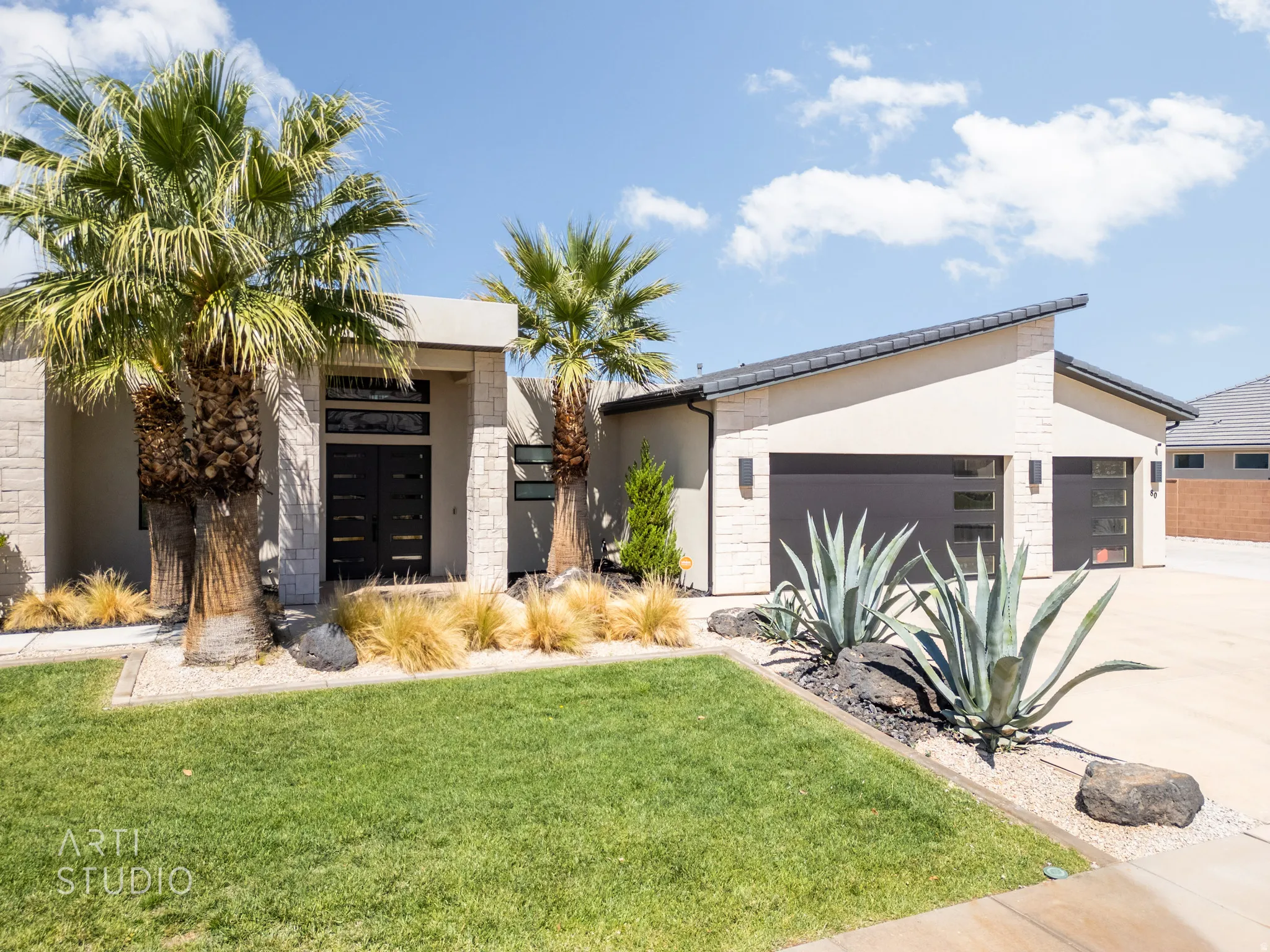 Modern single-story residence with a sloped roofline and light-toned exterior stone and stucco finishes