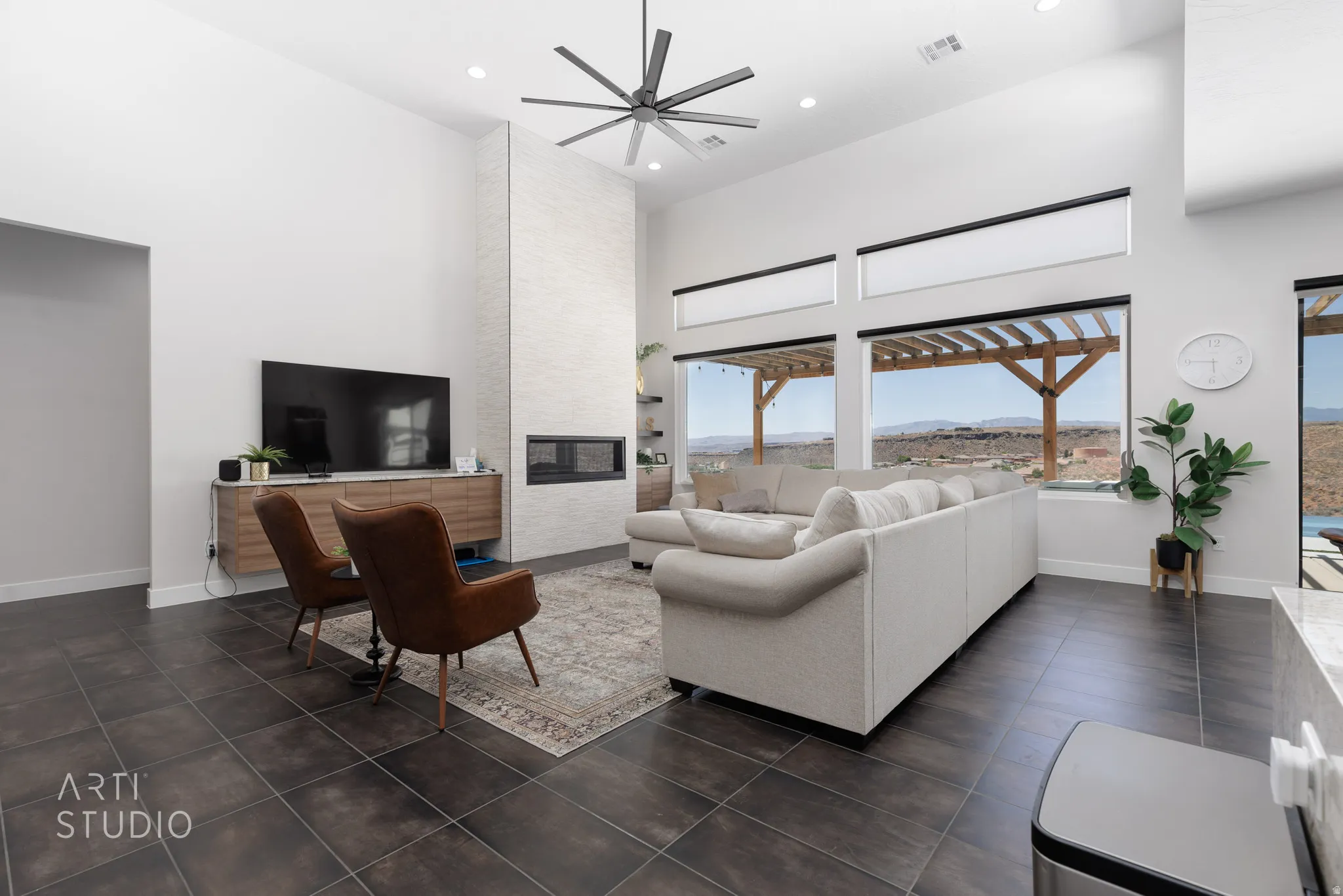 Spacious living area featuring high vaulted ceilings, dark tile flooring, and a linear fireplace integrated into a textured accent wall
