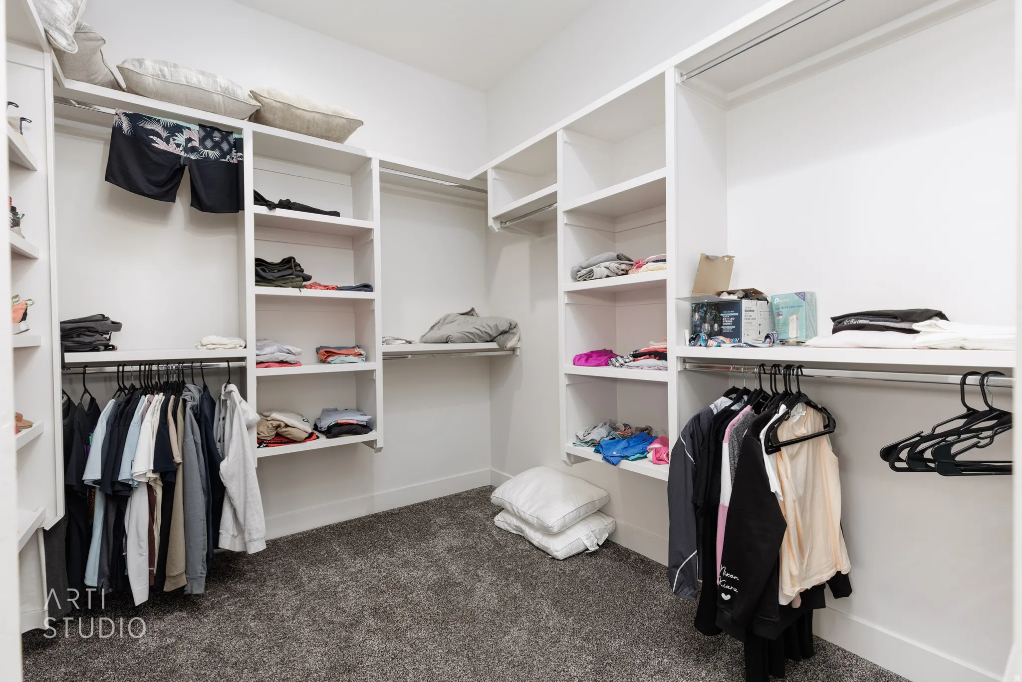 Spacious walk-in closet featuring built-in shelving, multiple hanging rods, and plush carpet flooring