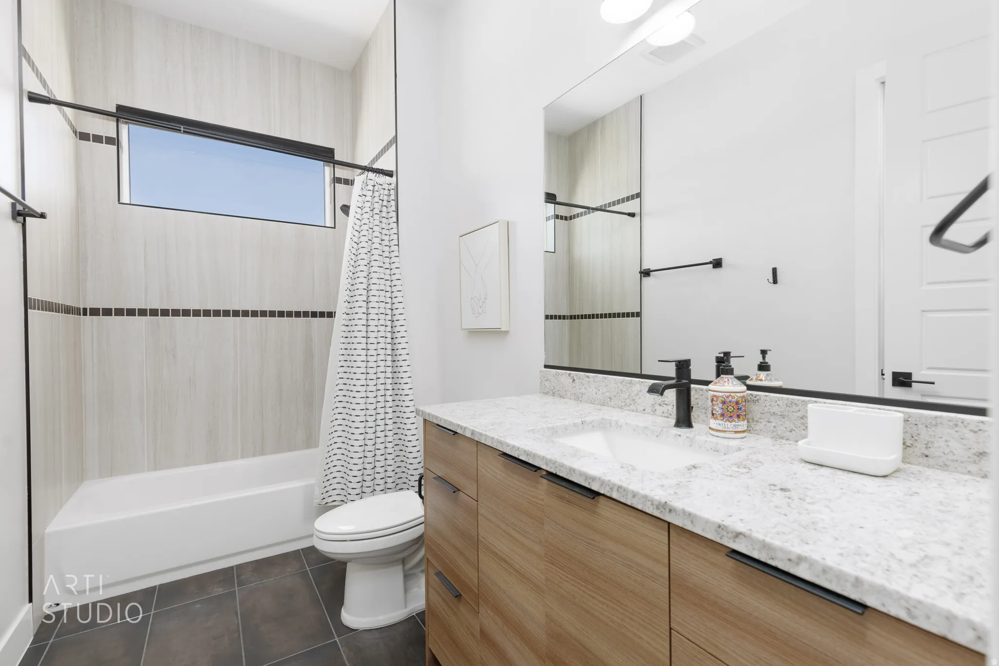 Bathroom featuring a wood-finish vanity with a white countertop, an undermount sink, and matte black fixtures