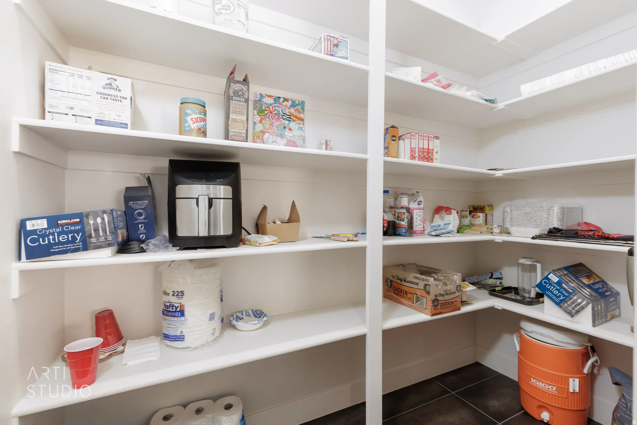 Walk-in pantry featuring white shelving, dark tile flooring, and ample storage space