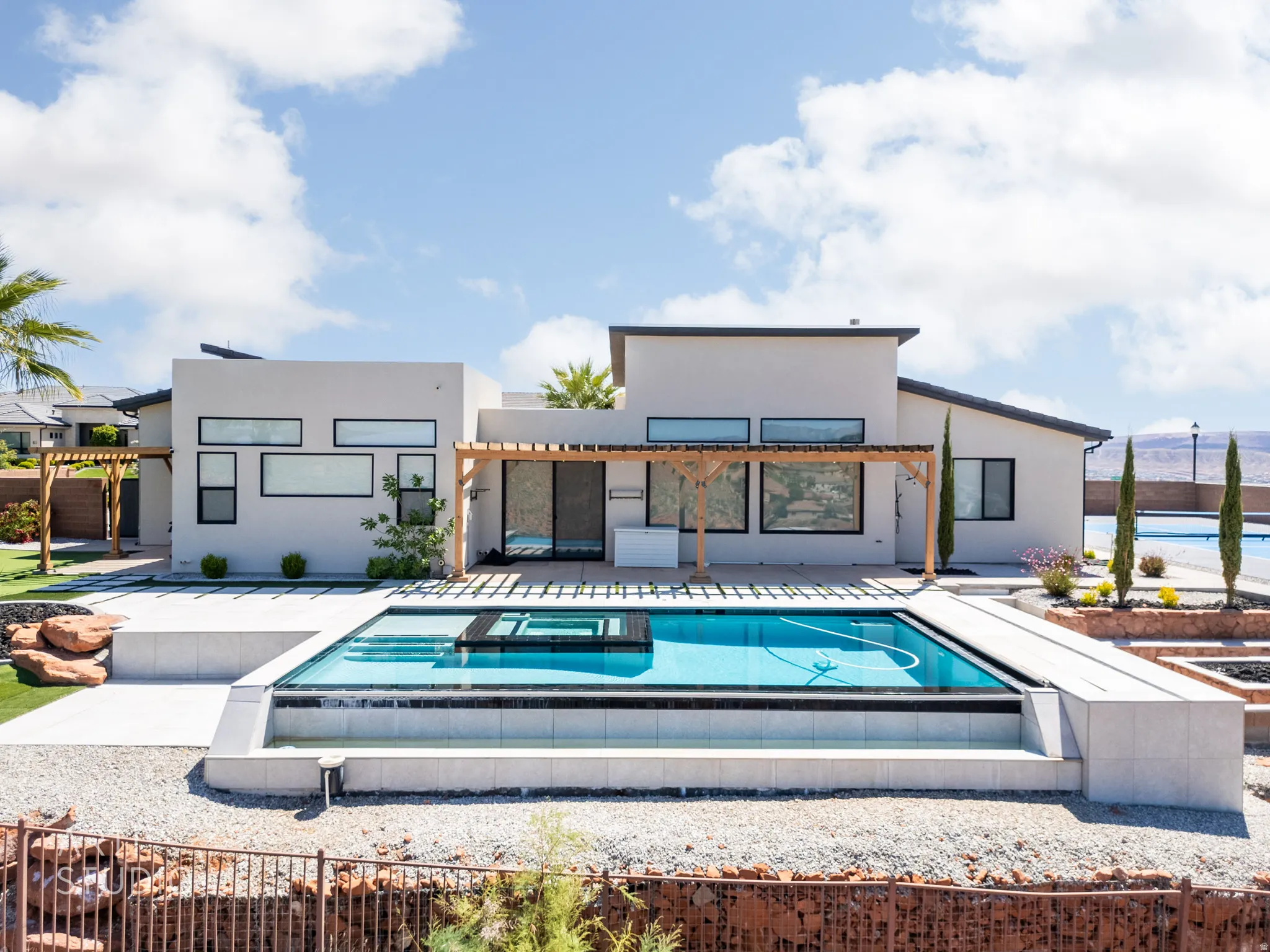 Modern exterior featuring a swimming pool with an integrated cover, extensive patio space, and a wooden pergola structure
