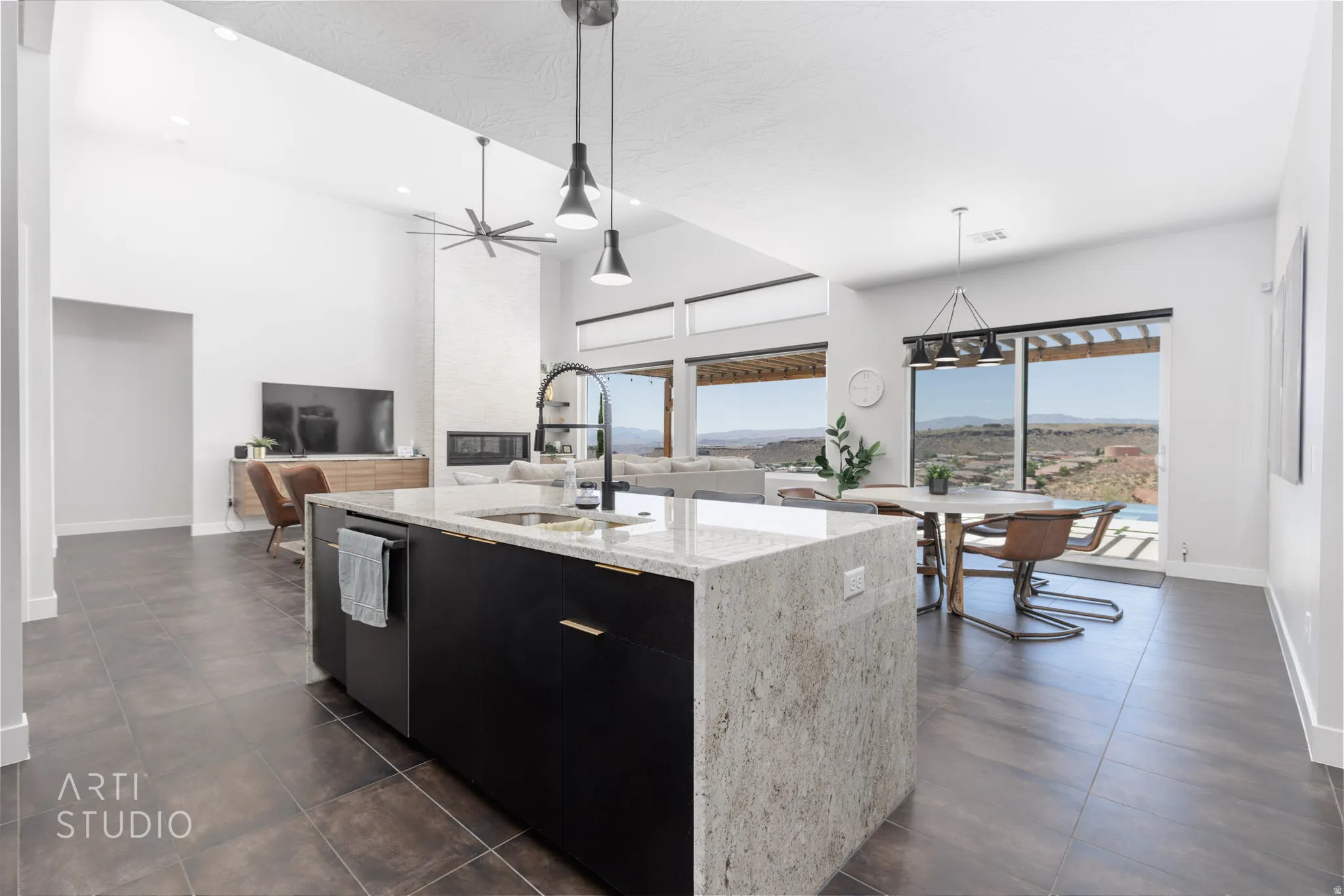 Spacious open-concept living area featuring a kitchen island with light-toned countertop and dark cabinetry