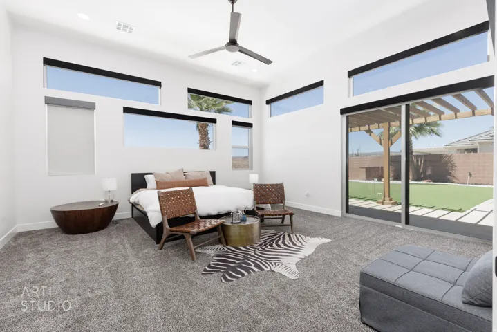 Vaulted ceiling with a contemporary ceiling fan, numerous clerestory windows with roller shades, and a sliding glass door leading to a backyard with artificial turf and a wooden pergola