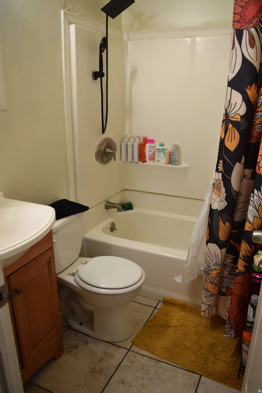 Bathroom featuring a white tub and shower combination with a black matte showerhead, a white toilet, and a wood-finish vanity with a white countertop