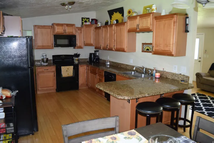 Kitchen featuring wood-finish flooring, light wood cabinetry, and speckled countertops