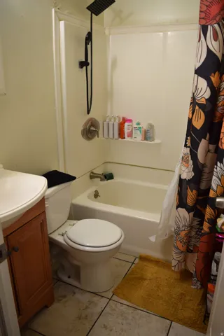 Bathroom featuring a white tub and shower combination with a black matte showerhead, a white toilet, and a wood-finish vanity with a white countertop