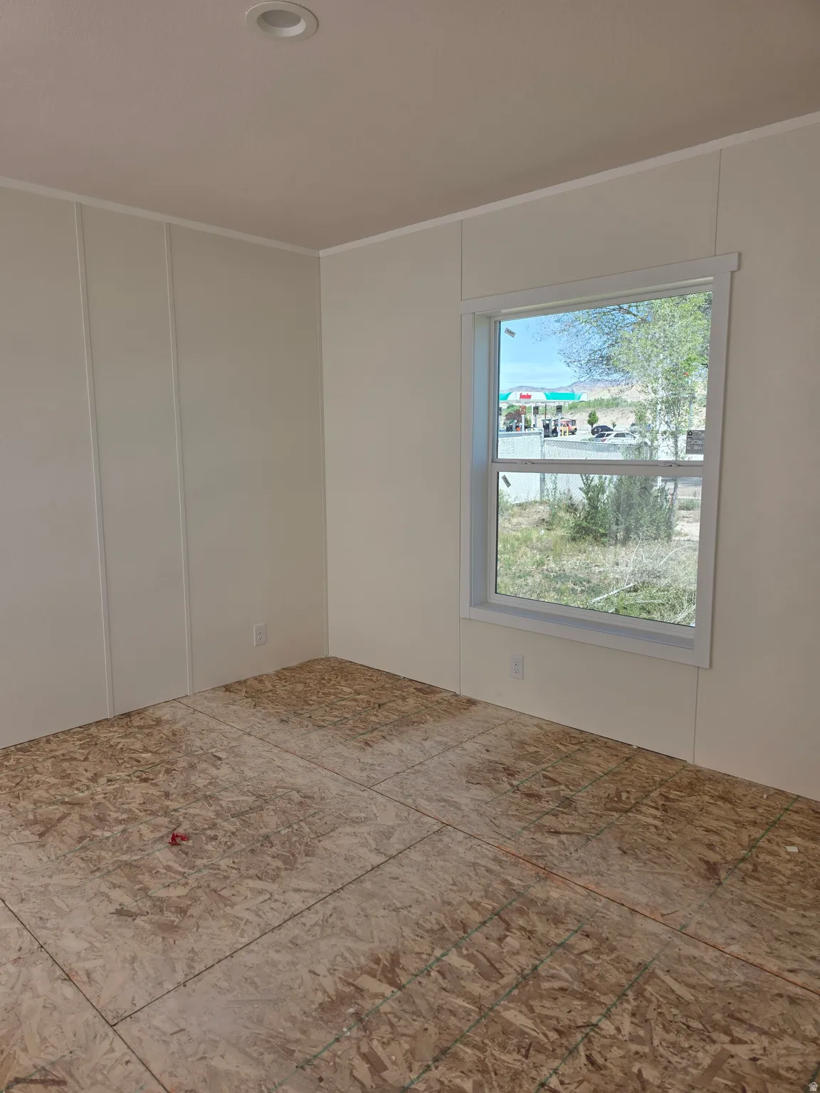 Room featuring light-colored panel walls, a single window with white trim, and a recessed ceiling light