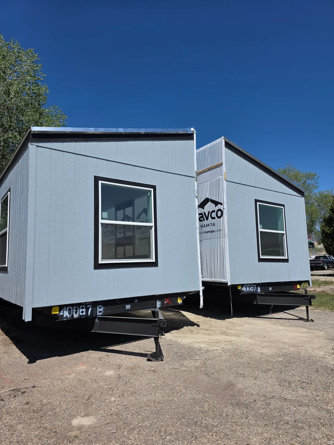 Two modular units featuring light blue siding and black trim around windows
