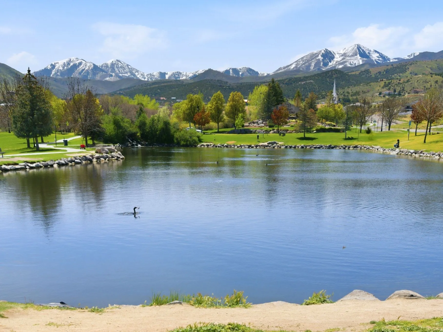 Expansive outdoor setting featuring a large body of water, green lawns, and mature trees.
