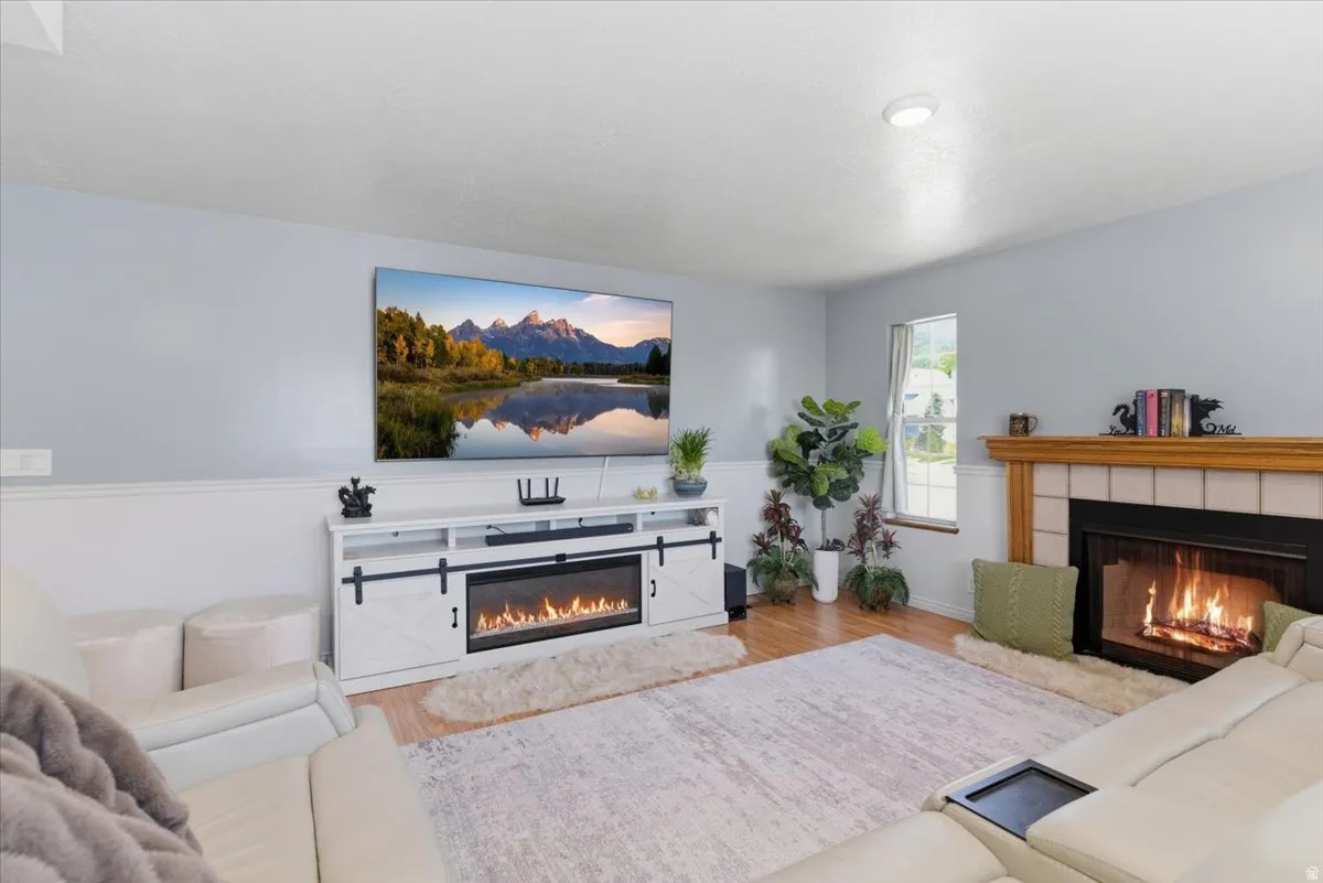 Living space featuring a tiled fireplace with a wood mantel, light wood-finish flooring, and light-toned walls