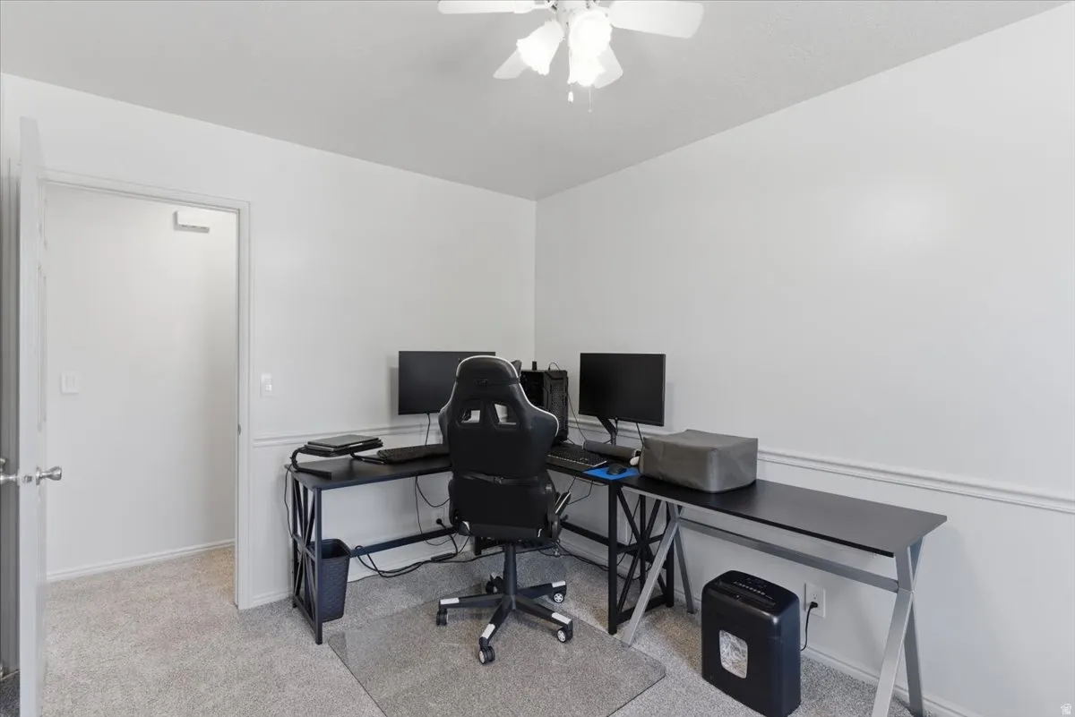 Room featuring light gray carpeting, white painted walls with a chair rail, a white ceiling fan, and a white interior door