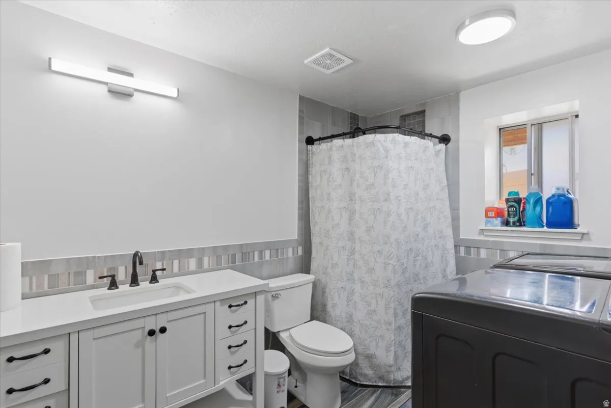 Bathroom featuring a white vanity with integrated sink, black hardware, and a quartz-finish countertop