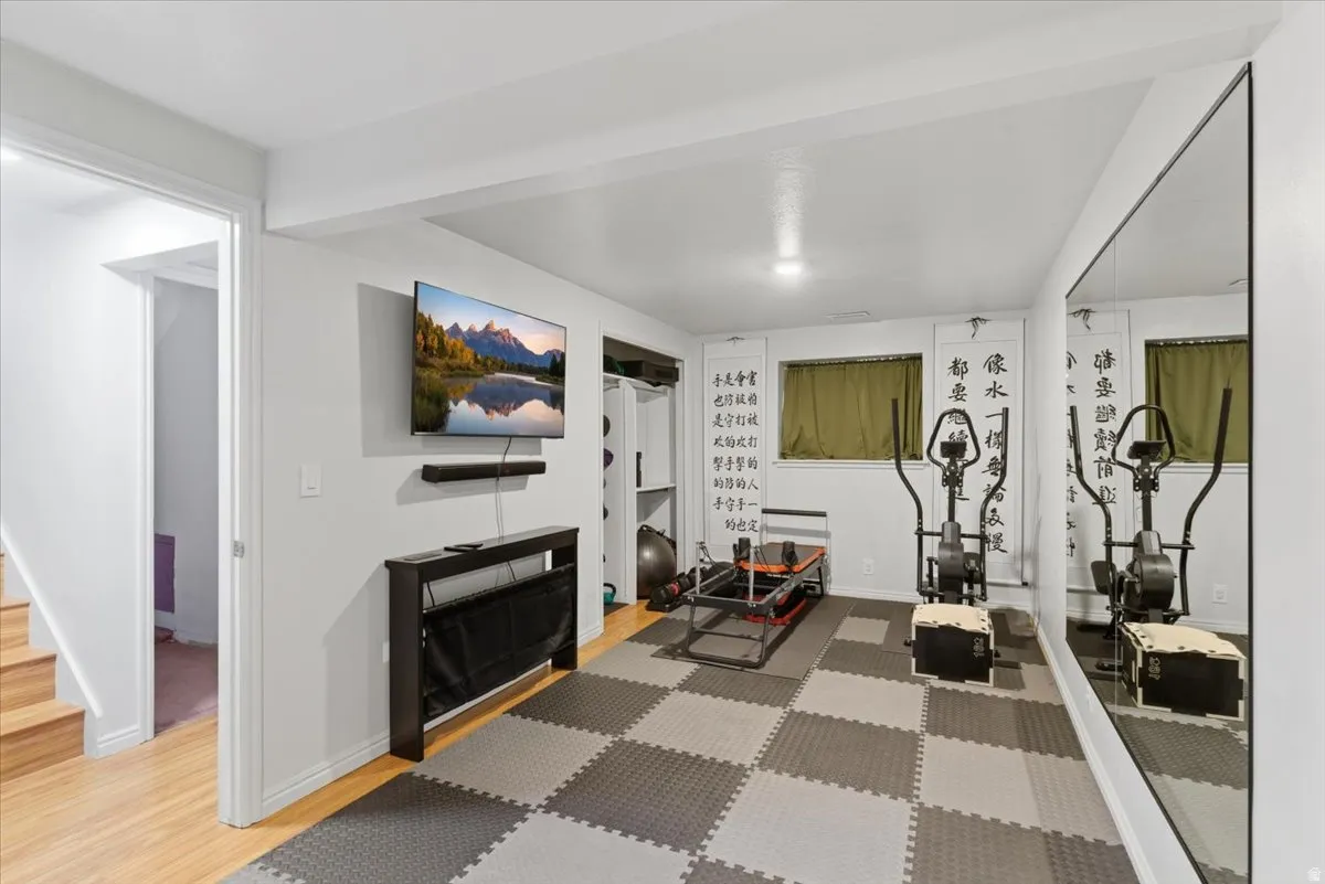 Finished basement area featuring checkerboard-patterned floor tiles, a full-wall mirror, and recessed lighting