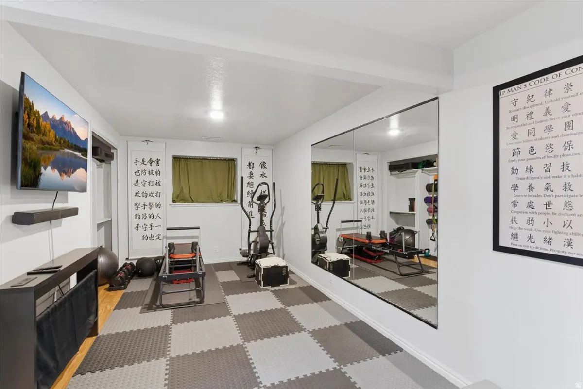 Dedicated fitness space featuring checkerboard-patterned flooring, recessed lighting, and a large wall-mounted mirror