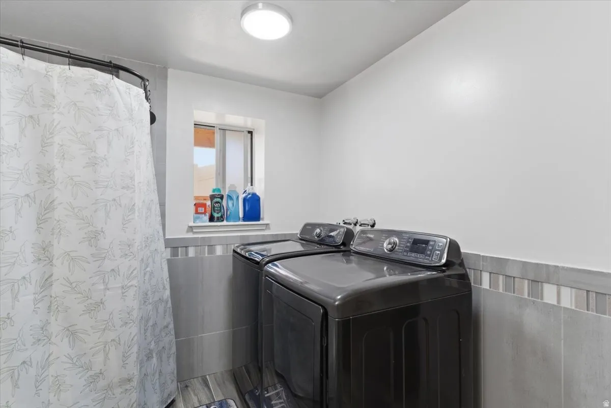 Utility area featuring tile flooring, a window, flush mount lighting, and a tile accent wall