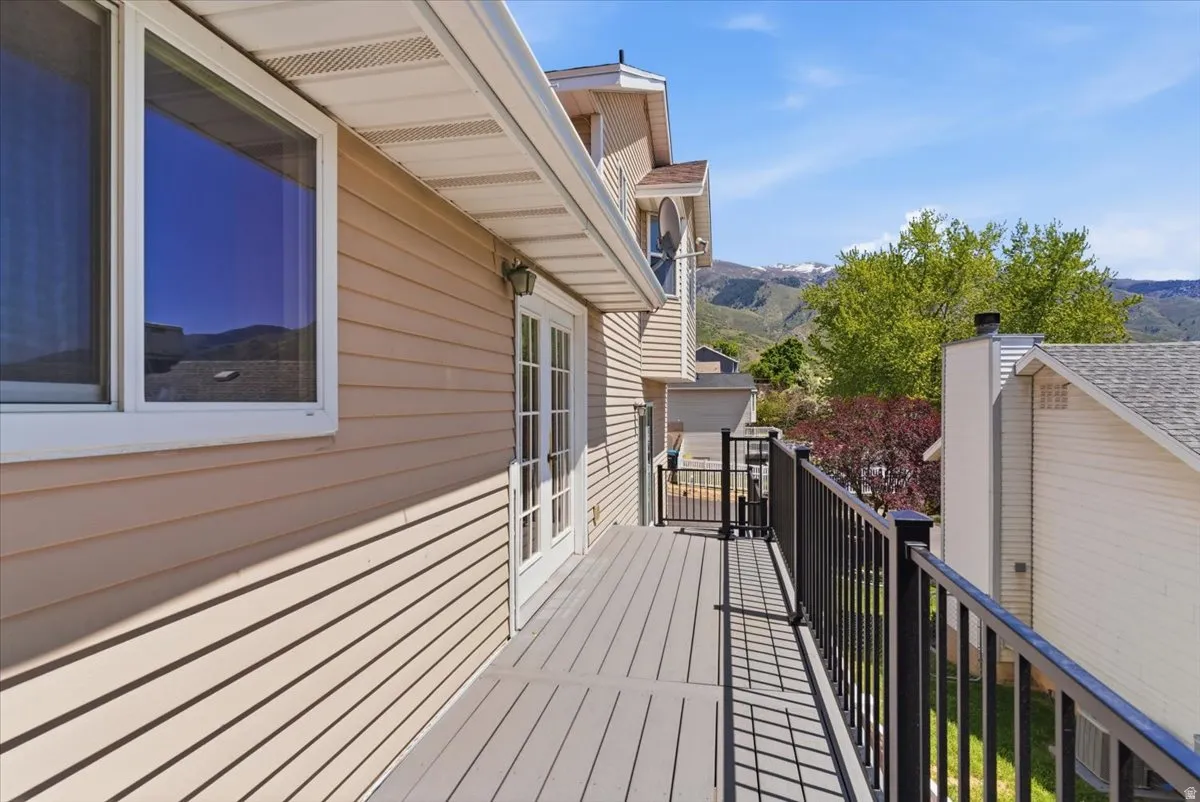 Private balcony featuring composite decking, black metal railings, and dual French doors