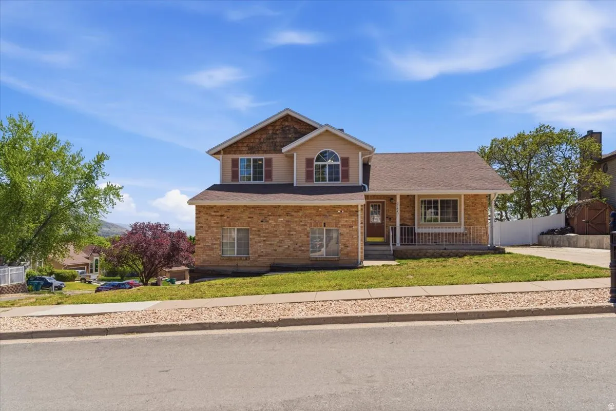 Two-story residence featuring a brick facade with complementary siding, a covered front porch, and a paved driveway