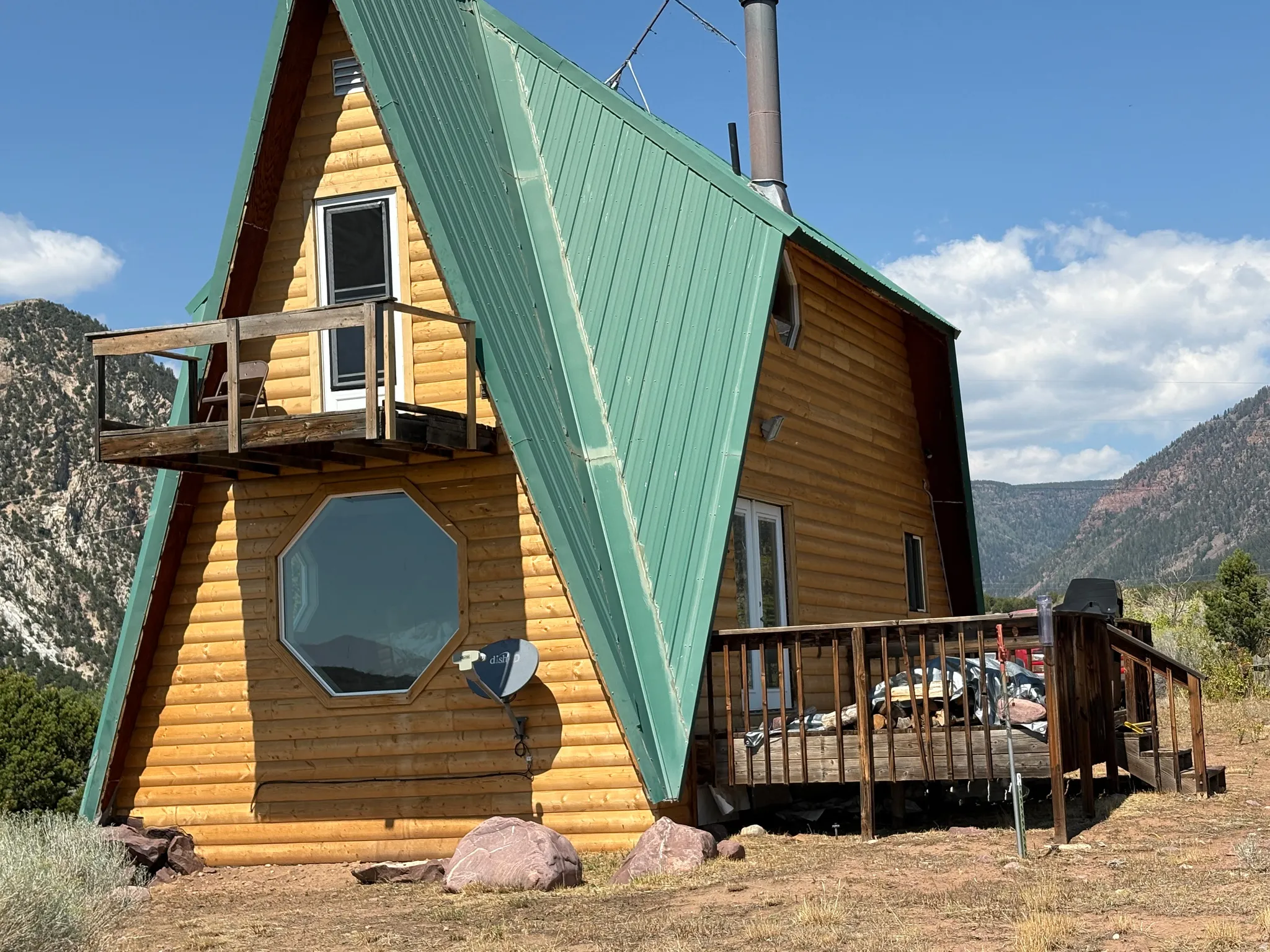 A-frame structure featuring a green metal roof and wood log siding