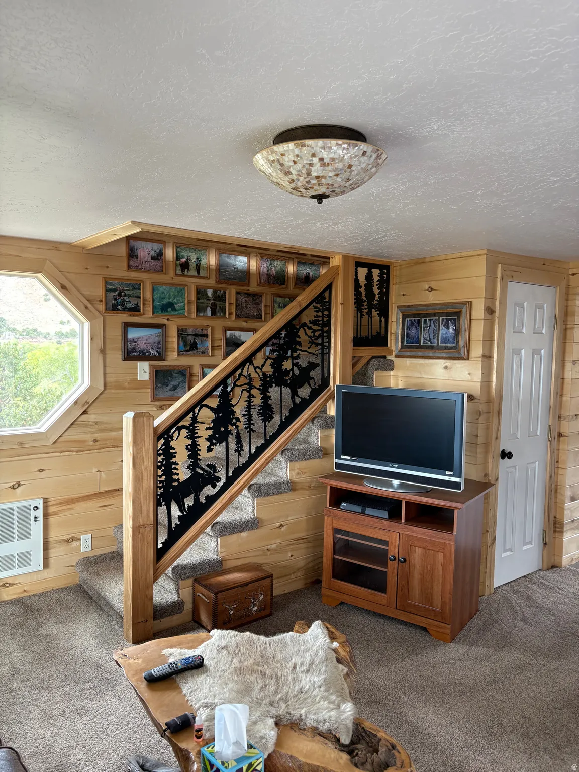 Staircase featuring custom metalwork railing with wildlife motifs, carpeted steps, and a natural wood newel post