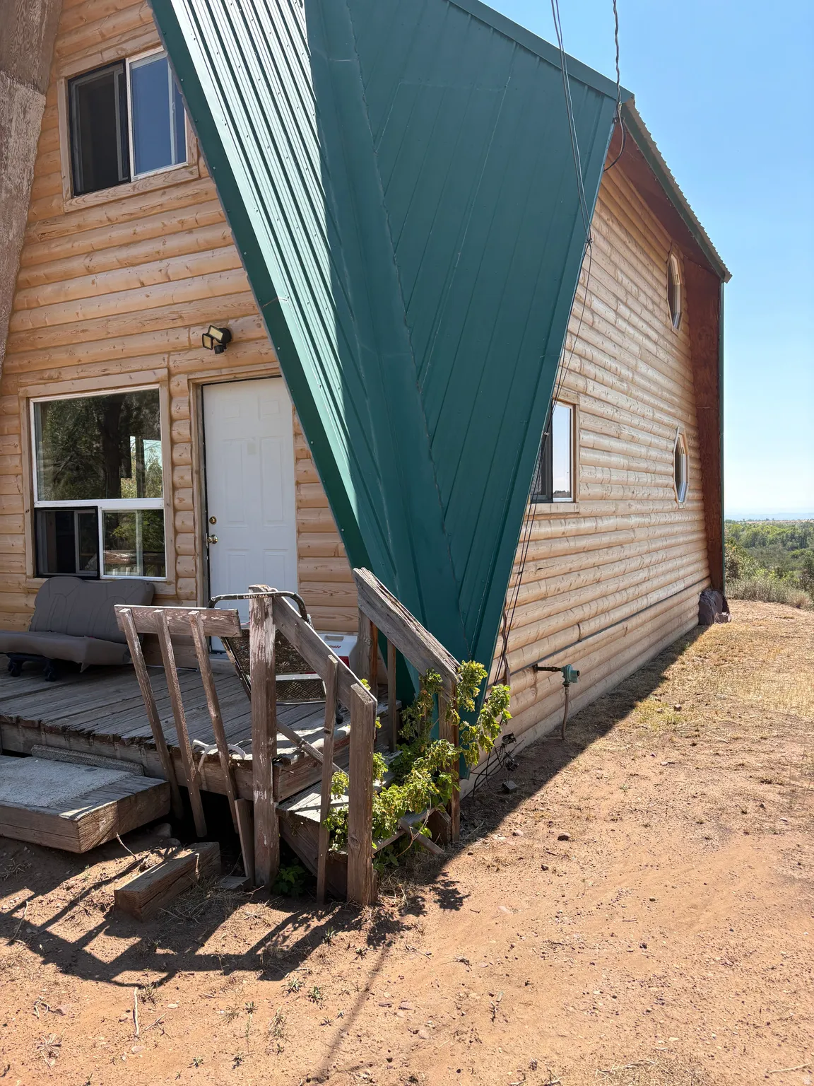 Log-sided A-frame structure featuring a green metal roof