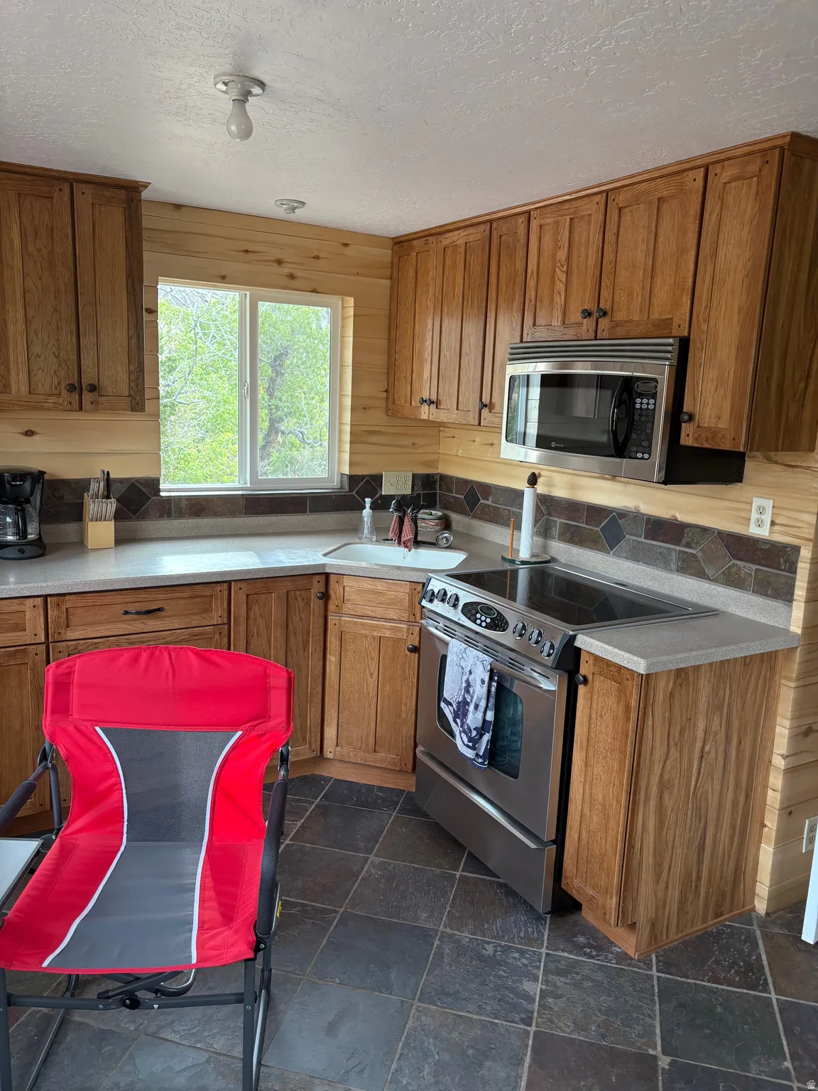 Kitchen featuring natural wood cabinetry, light-toned countertops, and a mosaic tile backsplash
