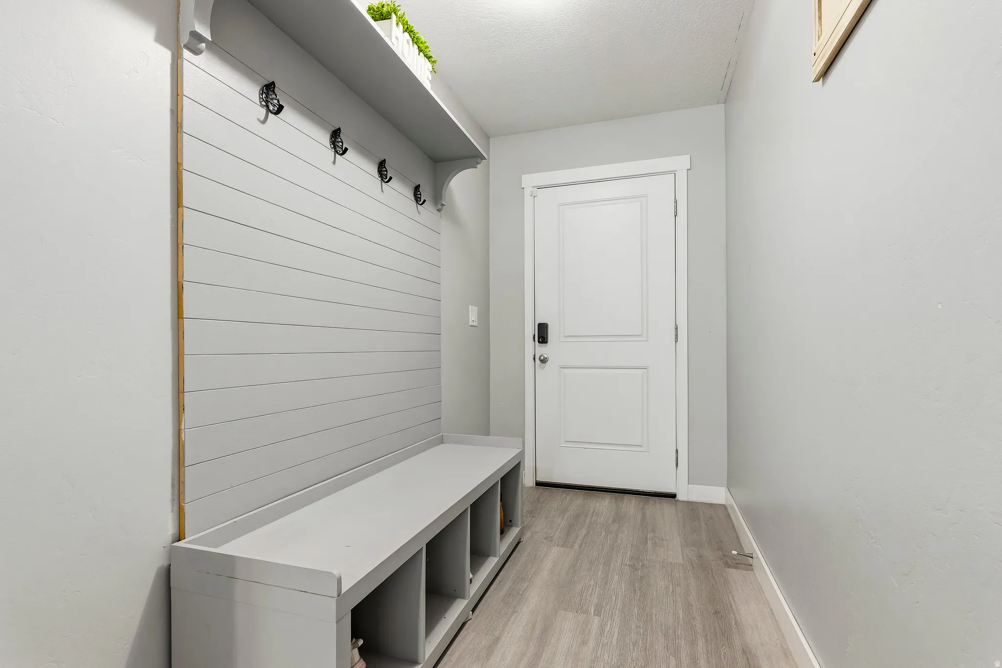 Built-in shiplap bench with individual storage cubbies and upper shelving with coat hooks