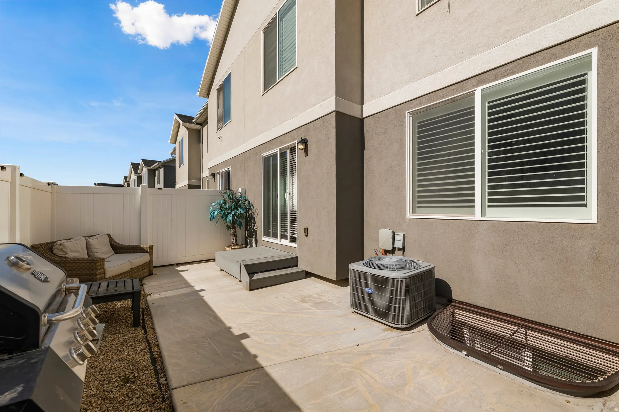 Private outdoor patio featuring concrete paving, a white privacy fence, and direct access through sliding glass doors