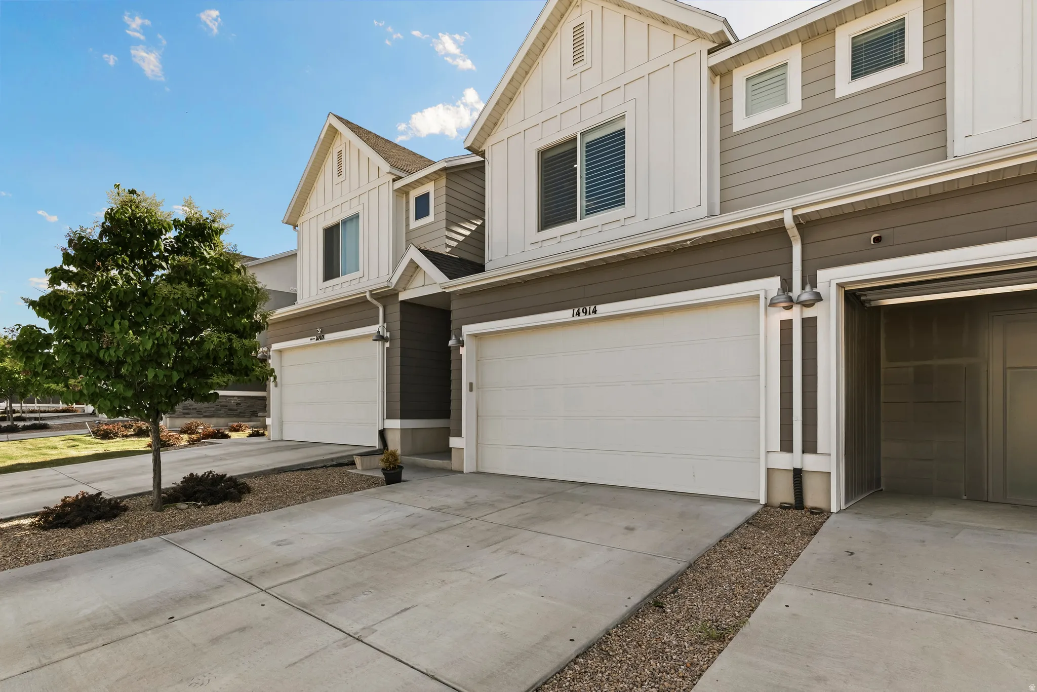 Modern townhome exterior featuring a two-tone facade, white garage doors, and individual driveways
