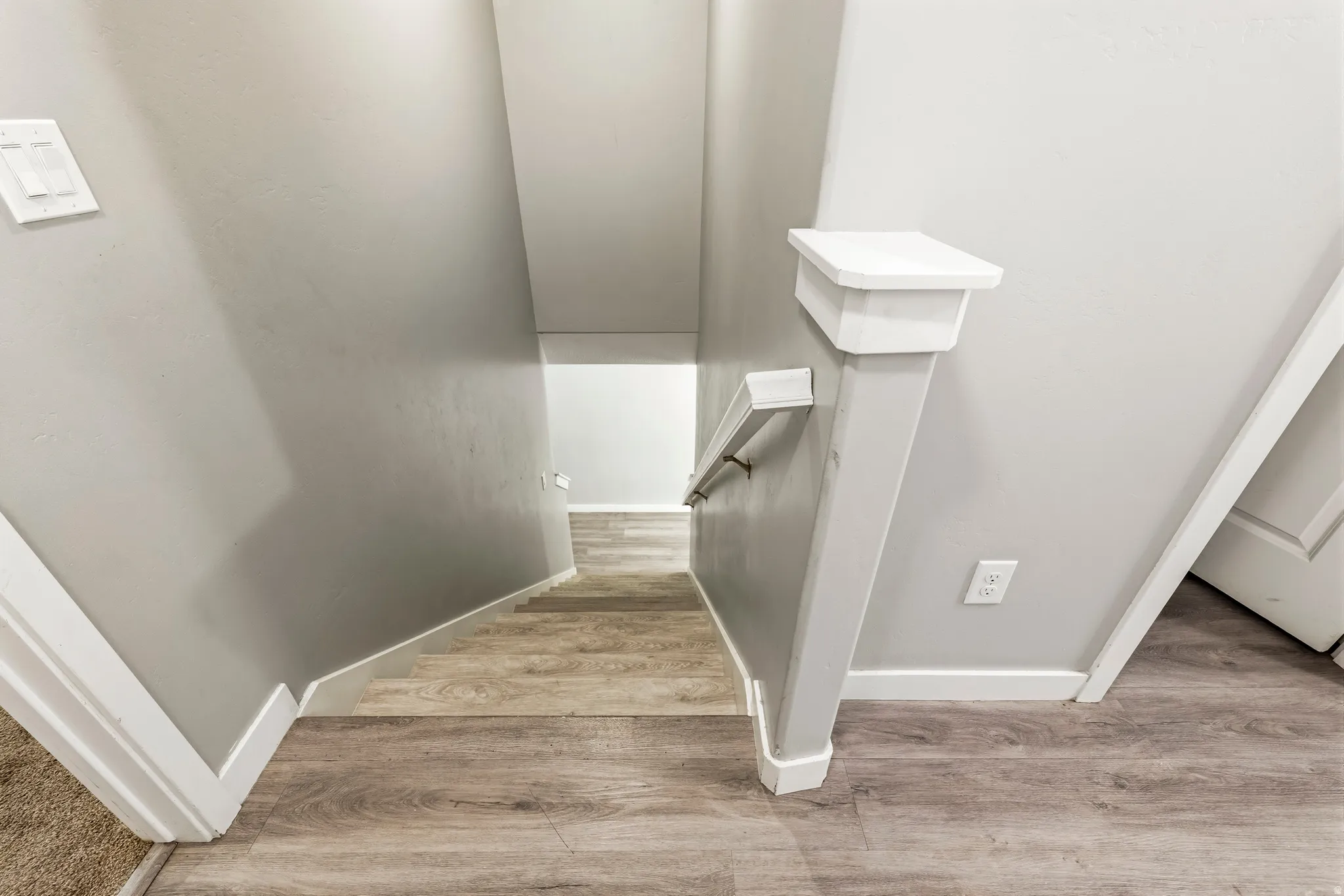Stairwell featuring wood-finish flooring, light gray wall paint, and white trim