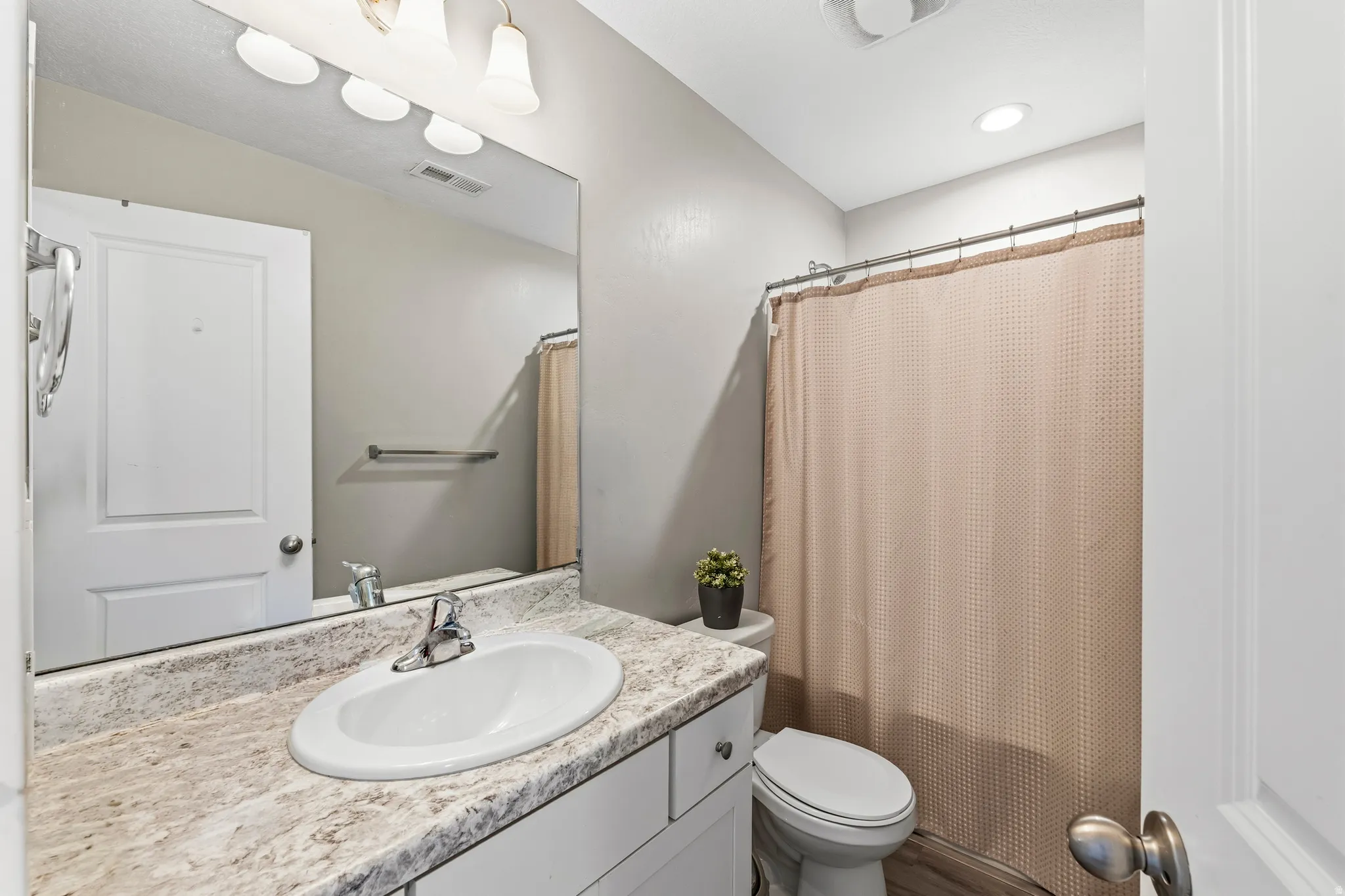 Bathroom vanity featuring an integrated sink, polished chrome faucet, and a stone-finish countertop