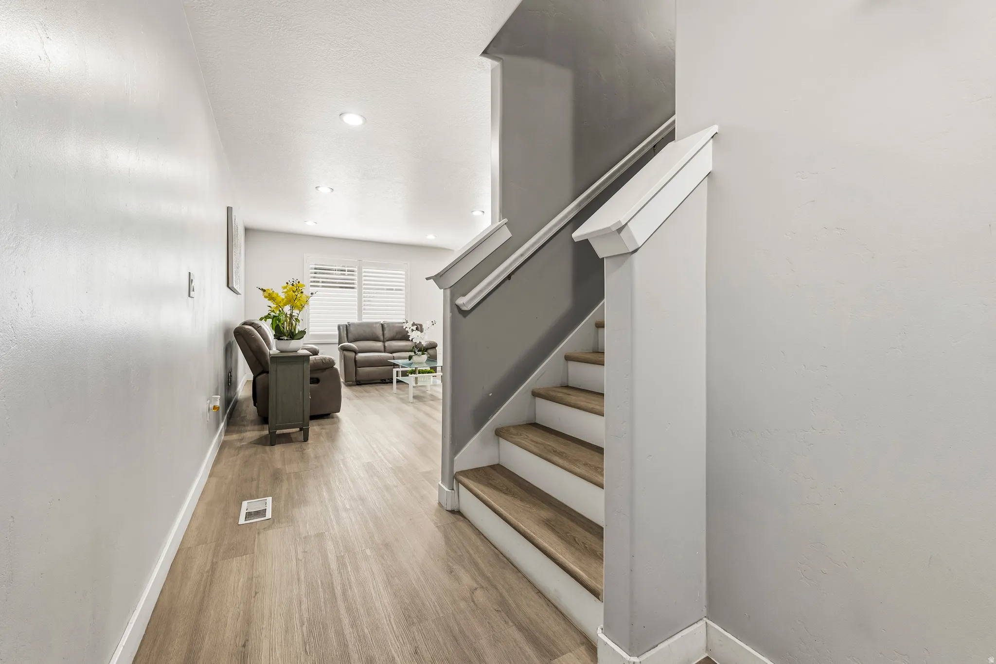 Interior staircase with wood-finish treads and white risers, complemented by a white handrail and newel post