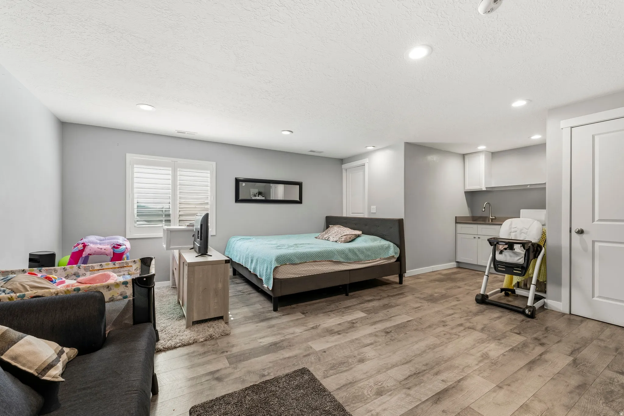 Spacious room featuring wood-finish flooring, recessed lighting, and a window with plantation shutters