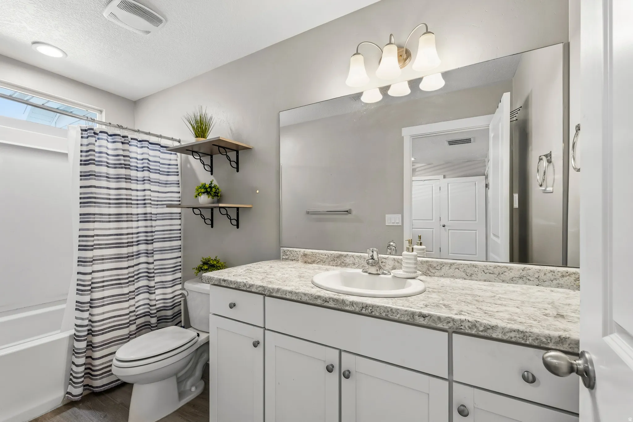 Bathroom featuring a single vanity with a laminate countertop, undermount sink, and a large wall-mounted mirror