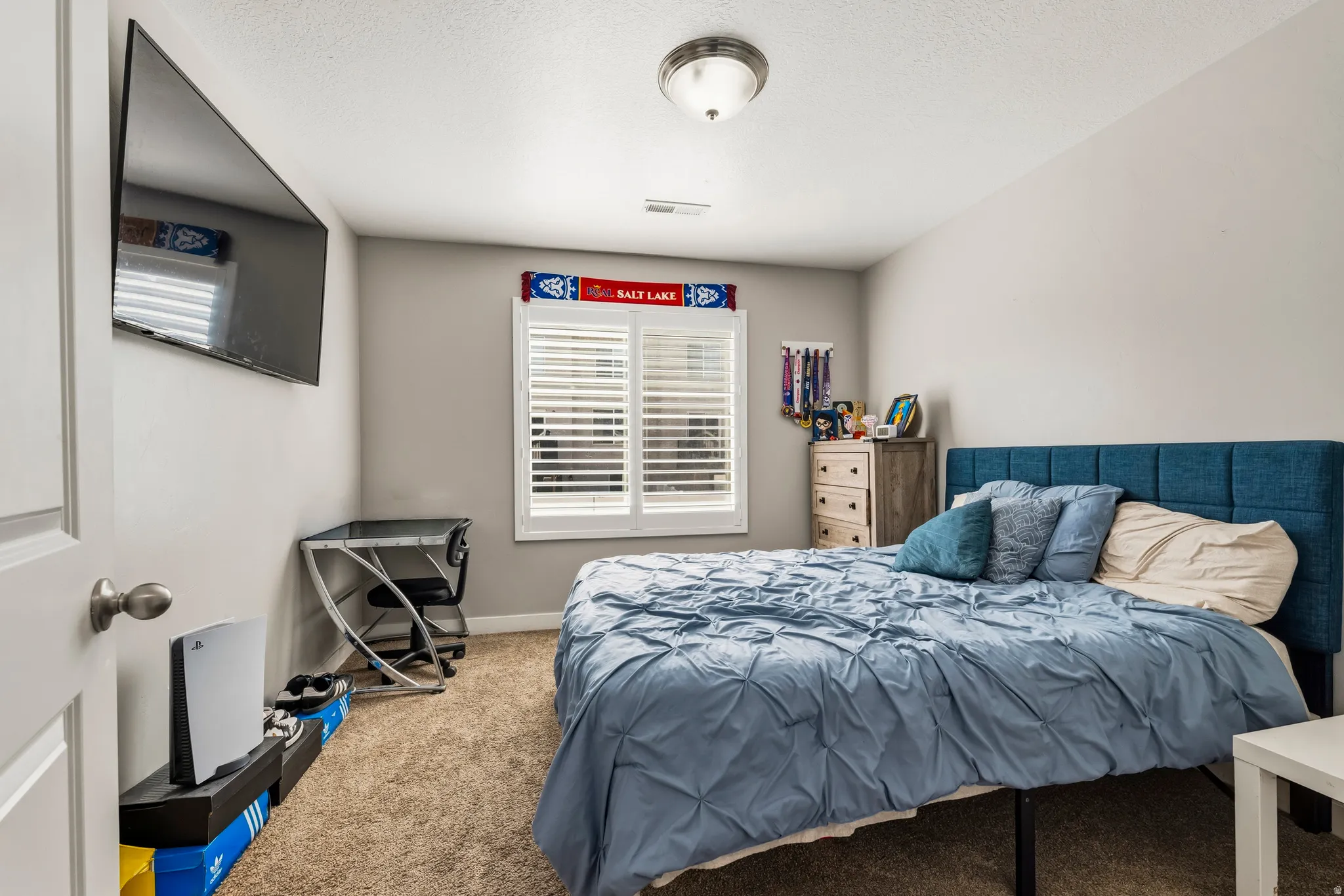 Bedroom featuring neutral wall paint, carpet flooring, a window with white plantation shutters, and a flush-mount ceiling light fixture