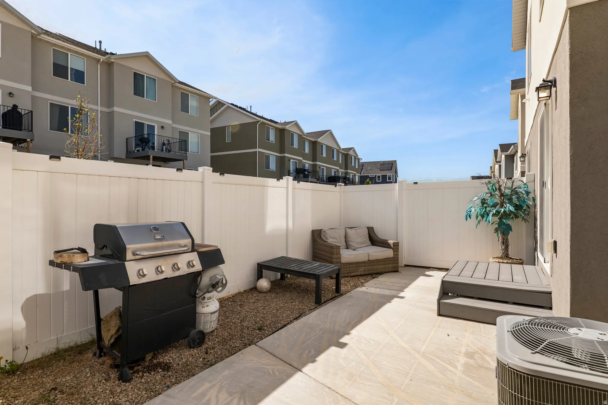 Private patio area featuring concrete paving, gravel landscaping, and a white privacy fence