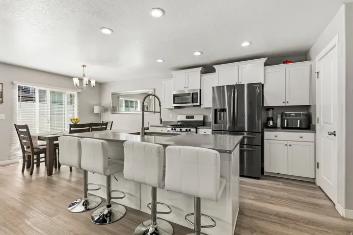 Open-concept kitchen with white shaker cabinetry, stainless steel appliances, and a central island with countertop seating