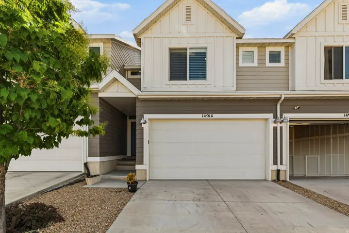 Contemporary townhome featuring a two-car garage, board and batten siding accents, and a covered entry