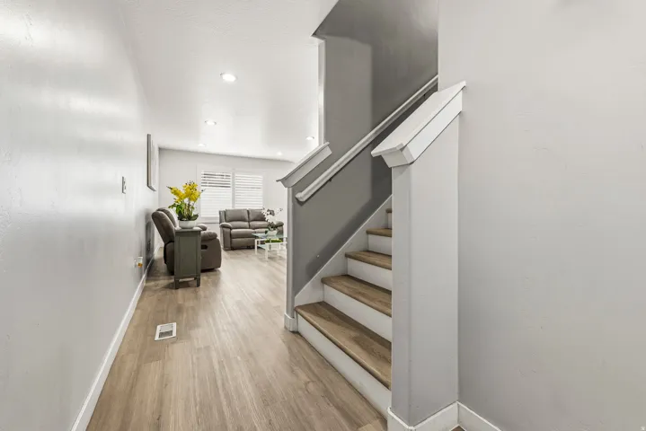 Interior staircase with wood-finish treads and white risers, complemented by a white handrail and newel post